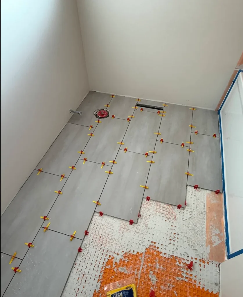 Bathroom tile floor being set over a waterproofing membrane with a tile leveling system in Boise, Idaho