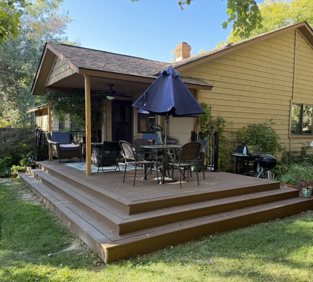 Composite deck with wraparound steps and a covered patio with a ceiling fan behind a Boise, Idaho home, built by Kemsley Construction