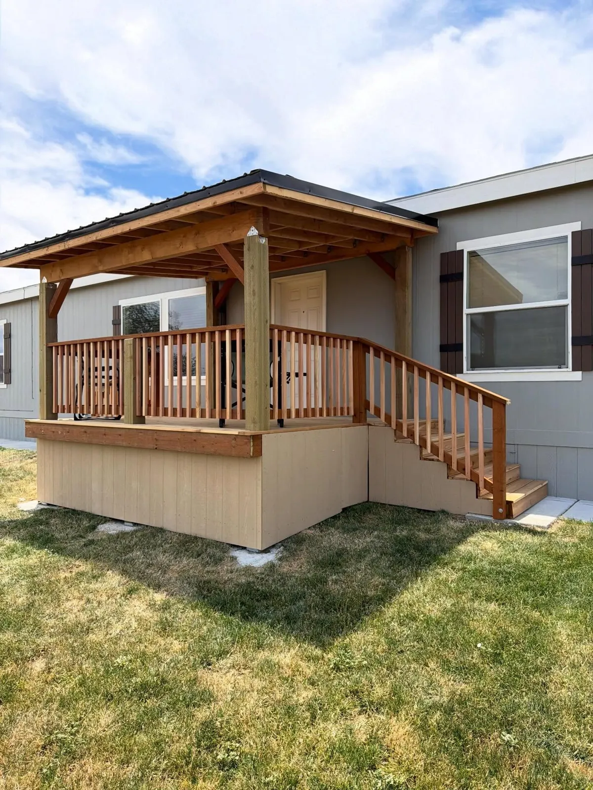 Custom covered deck with cedar railings, stairs and a timber-framed metal roof in Kuna, Idaho, built by Kemsley Construction