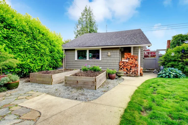 Custom backyard shed with shingle siding, a shingle roof and windows beside raised garden beds, custom sheds in Boise, Idaho