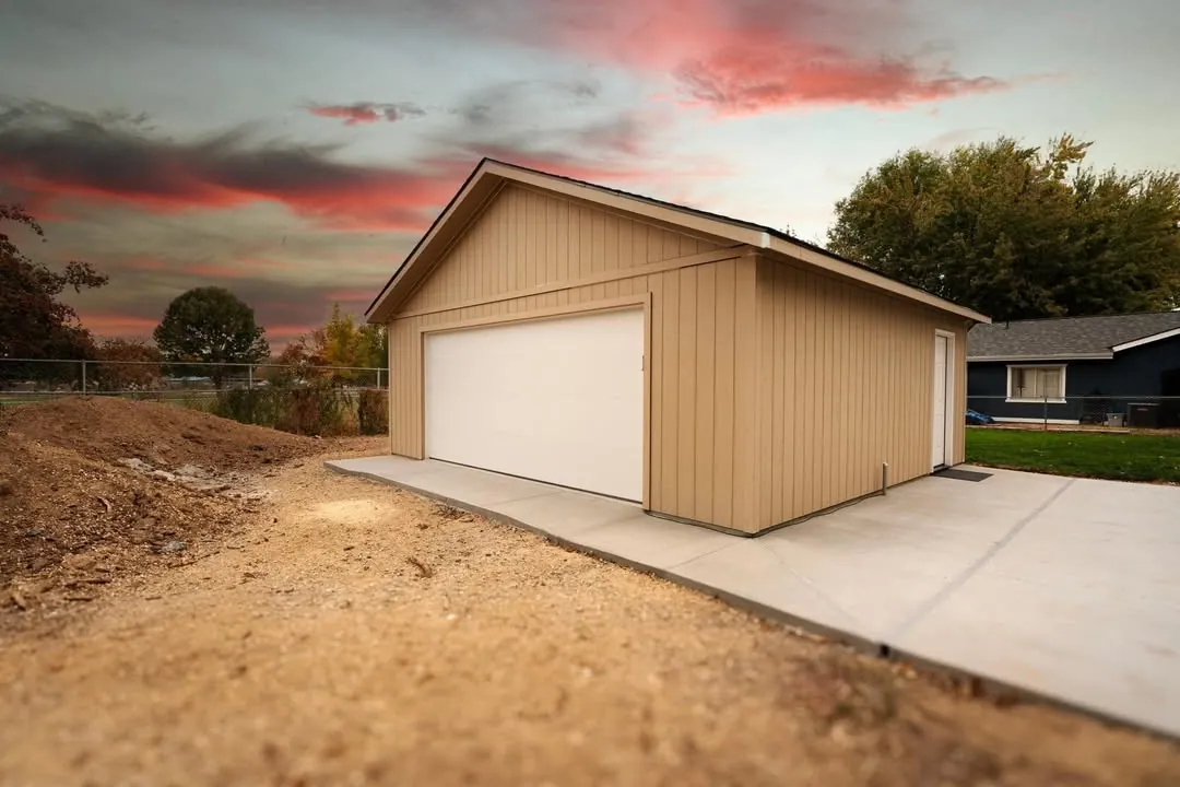 New detached two-car garage with vertical siding, a white overhead door and a concrete apron at sunset, garage builder in Boise, Idaho
