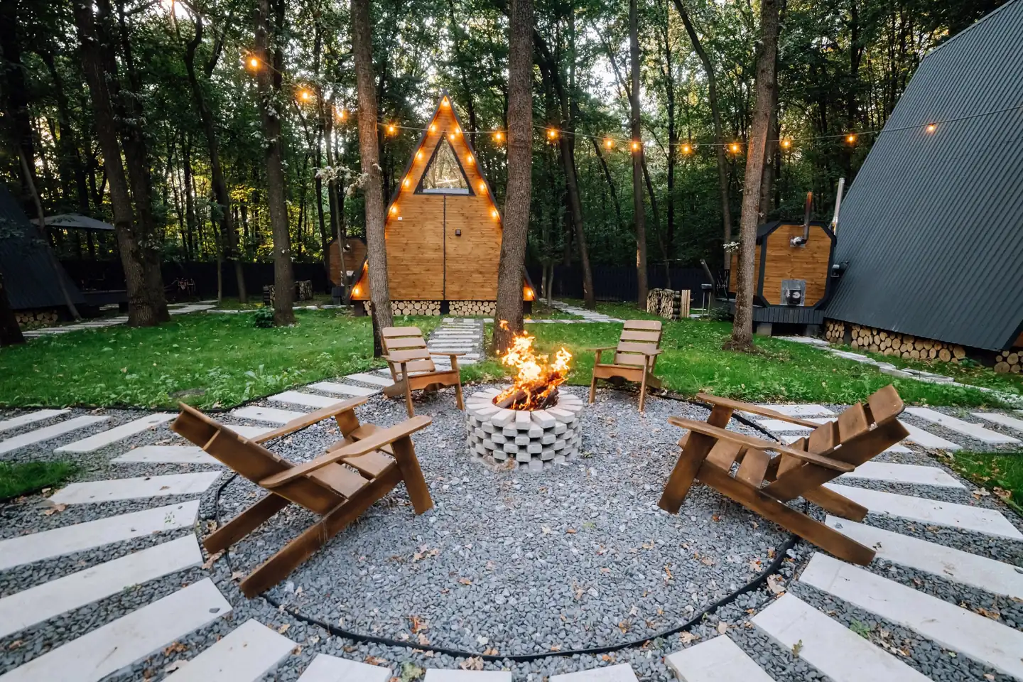 Backyard fire pit with Adirondack chairs and a gravel and paver seating circle under string lights, fire pits in Boise, Idaho