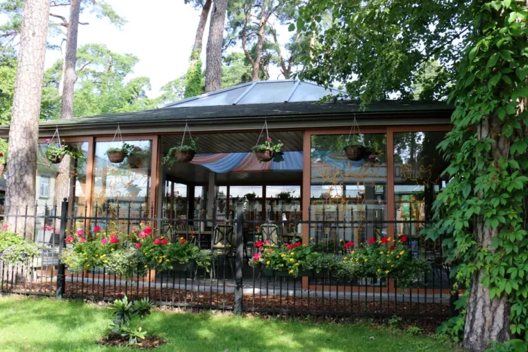 Glass-enclosed backyard gazebo with hanging flower baskets and a wrought-iron fence, custom gazebos in Boise, Idaho
