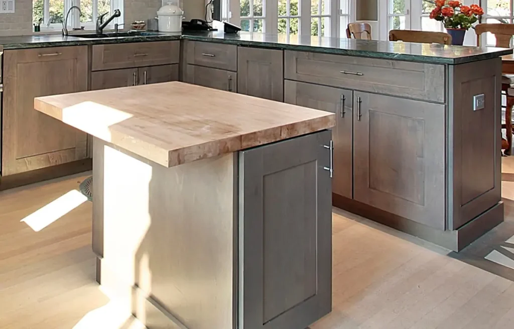 Kitchen island with a butcher block countertop and gray shaker cabinets in a remodeled kitchen