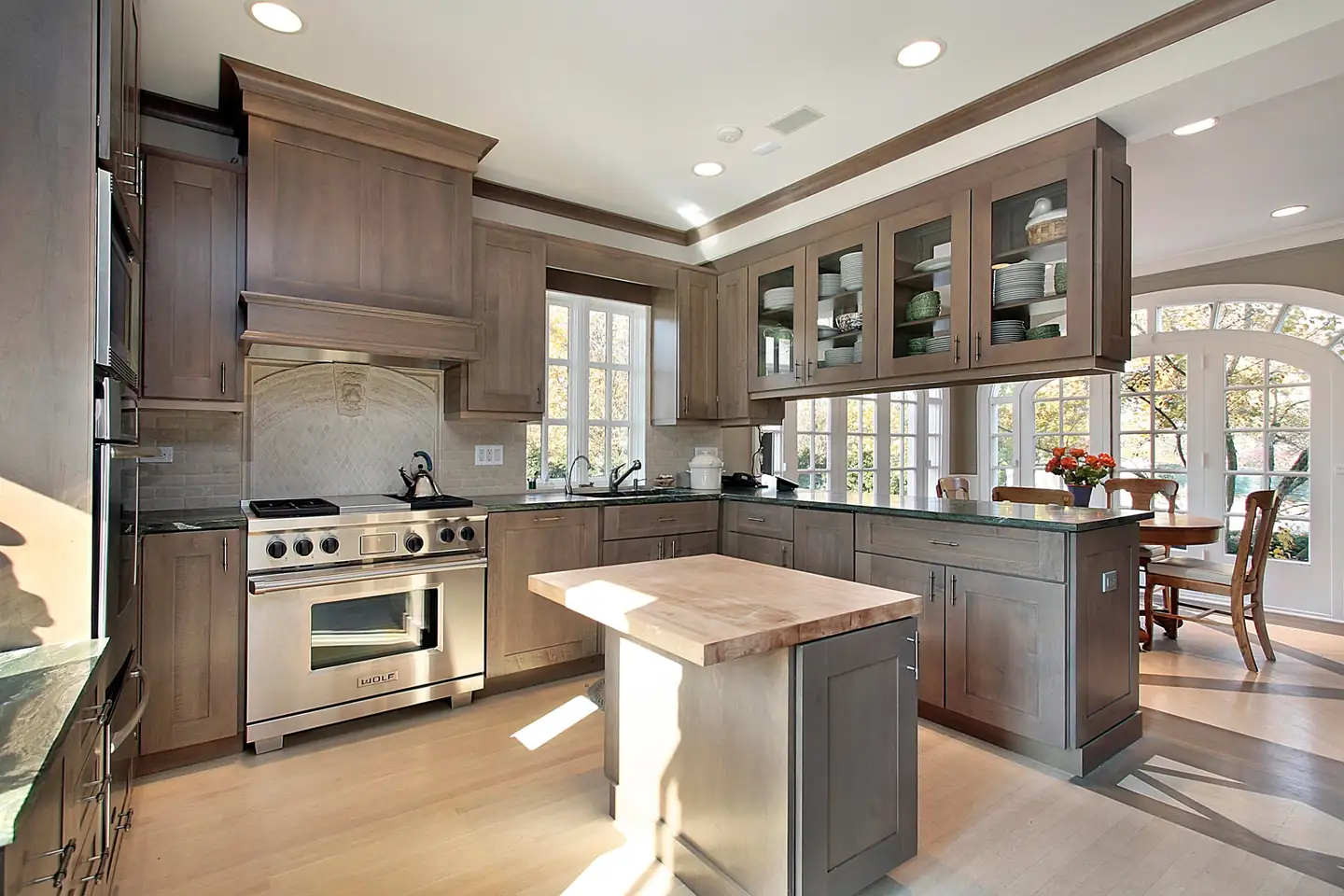 Remodeled kitchen with gray-stained shaker cabinets, glass-front uppers, a butcher block island and bright windows, kitchen remodels in Boise, Idaho