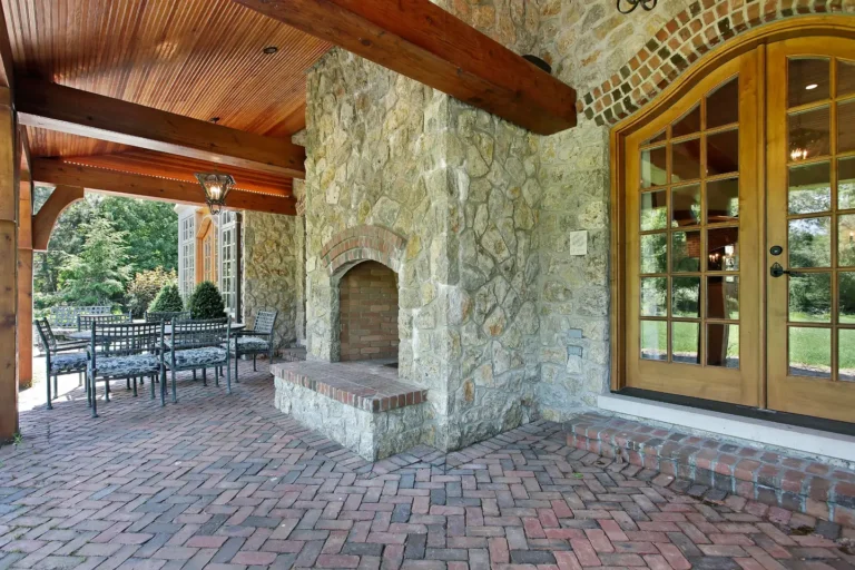 Stone outdoor fireplace with an arched brick firebox and raised hearth under a covered patio, outdoor fireplaces in Boise, Idaho