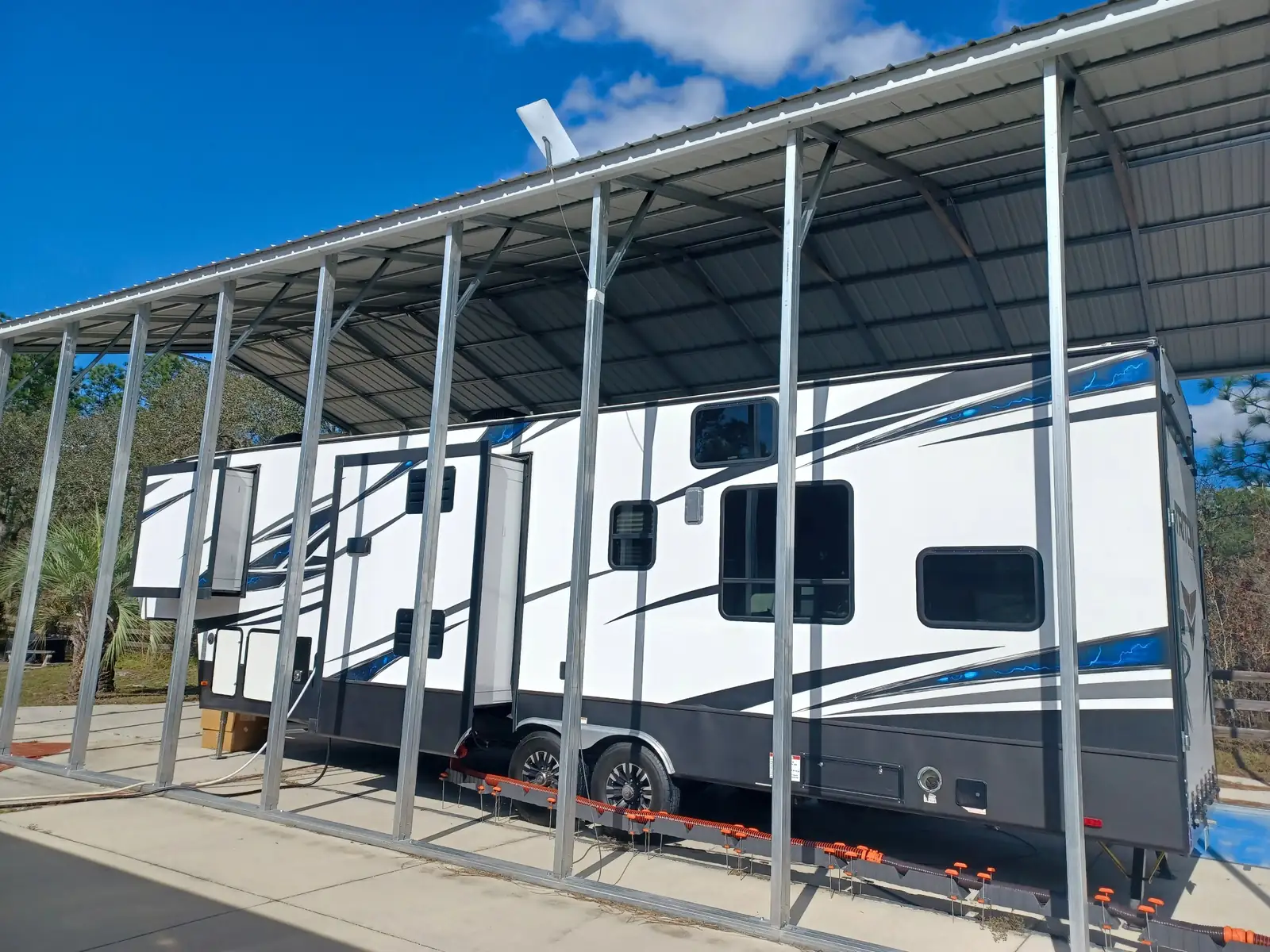 Fifth-wheel RV parked under a tall metal RV cover with a steel frame and corrugated roof, RV covers in Boise, Idaho