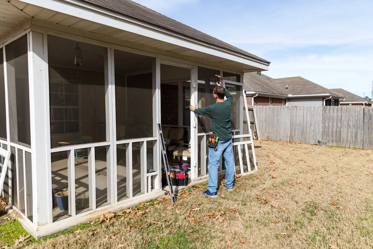 Contractor installing a screen door on a covered screened porch attached to a brick home, screened porches in Boise, Idaho