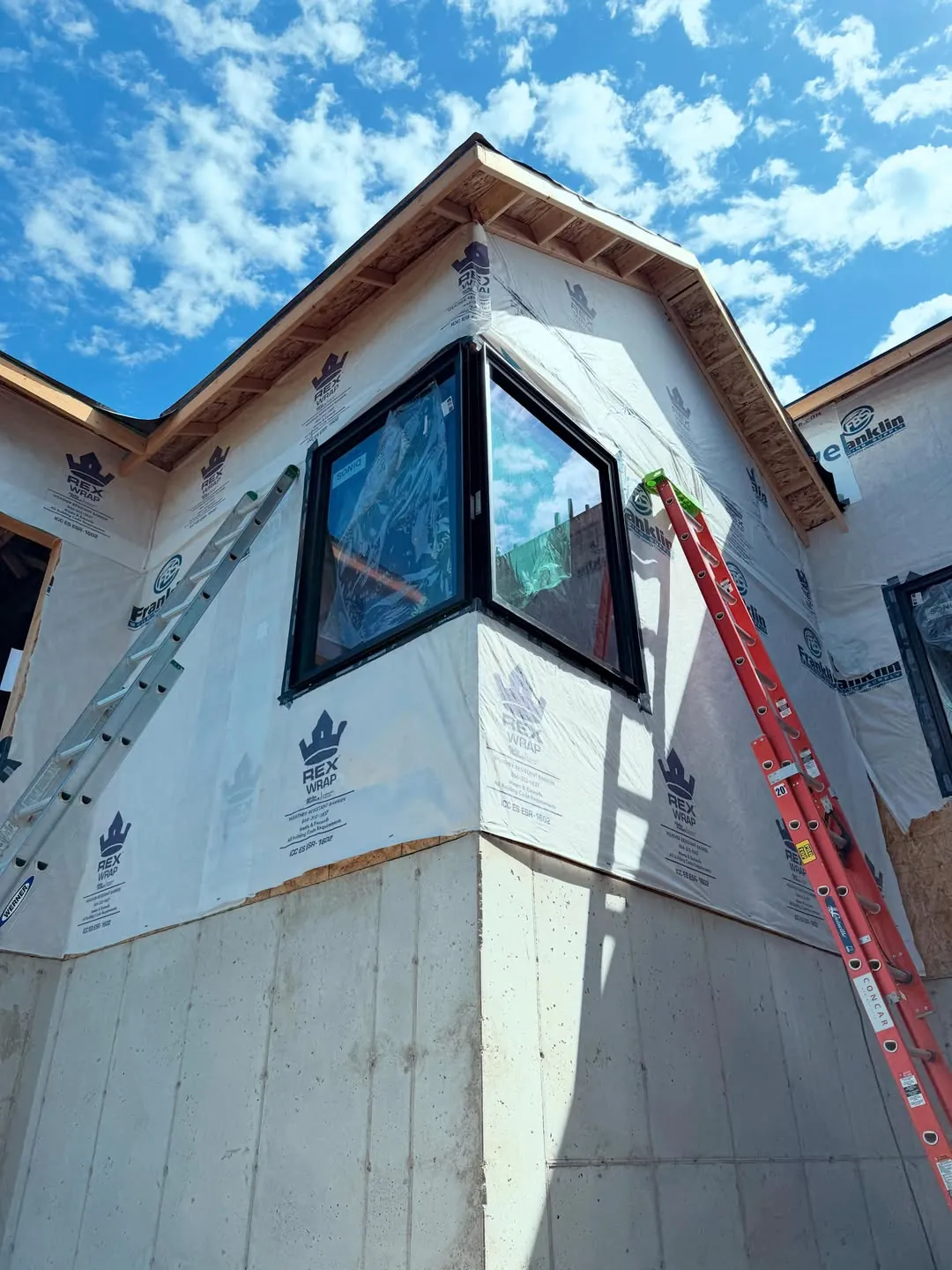 New corner windows installed on a home under construction with weather-resistant house wrap in Idaho
